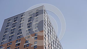 High rise apartment building surrounded by blue sky. Action. Newly build residential multi storey house of grey and