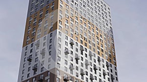 High rise apartment building surrounded by blue sky. Action. Newly build residential multi storey house of grey and