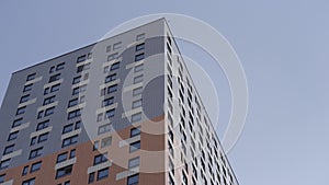 High rise apartment building surrounded by blue sky. Action. Newly build residential multi storey house of grey and