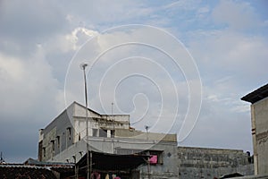 A high-rise building in a housing estate in a city with various types of architecture and a cloudy blue sky background. Perfect fo