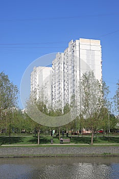 High-rise building in a residential area of the city on the shore of a pond, view from ground level