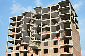 A high-rise building under construction. Building contractors on a building platform are laying masonry vertical walls of a