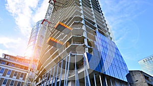 High rise building under construction. Installation of glass facade panels