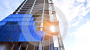 High rise building under construction. Installation of glass facade panels