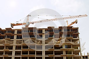 high-rise building under construction and two cranes against the sky