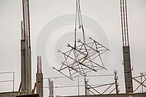 A high-rise construction crane lifts the lattice structure into the zone of building floor formation