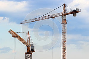 High-rise construction cranes on a blue sky background