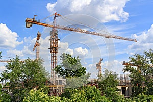 High-rise cranes at the construction site against blue sky