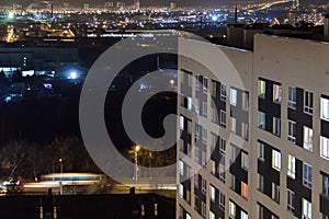 High-rise modern building in the evening window lights.Casual urban city life. Traffic on the road.From tower rooftop