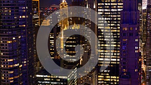 High rise office buildings tower above the bustling streets of New York at night