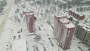 High-rise residential buildings and a city road are covered with white snow.