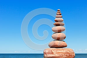 High Rock zen pyramid of pink stones on a background of blue sky and sea