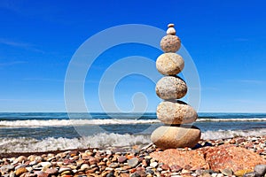 High Rock zen pyramid of white and pink pebbles on a background of blue sky and sea