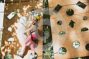 High ropes walk. Cute school little girl boy enjoying a sunny day in a climbing adventure activity park. Go Ape