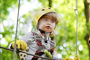 High ropes walk. Helmet and safety equipment. Child concept. Happy Little child climbing a tree. Rope park - climbing