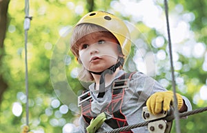 High ropes walk. Helmet and safety equipment. Child concept. Happy Little child climbing a tree. Rope park - climbing