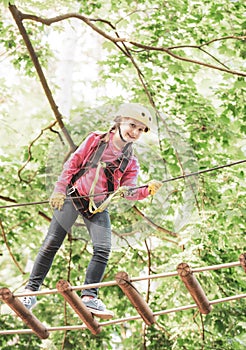 High ropes walk. Helmet - safety equipment for Child playing. Little child climbing in adventure activity park with