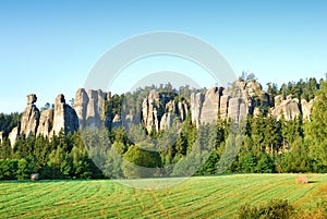 High sandstone towers rising from a forest in Adrspach