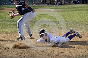 High school baseball player slides into base