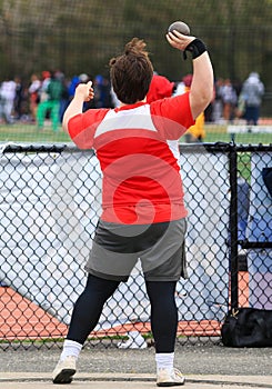 High school boy throwing the shot put in an outdoor circle