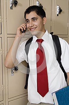 High School Boy Using Cell Phone By School Lockers