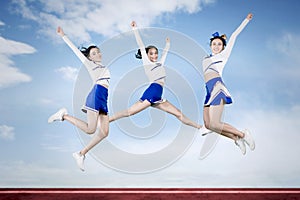 High school cheerleaders jumping with blue sky