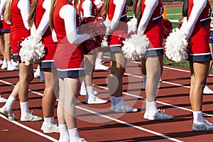 High school cheerleaders standing on the track during a football game
