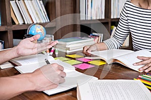 High school or college student group sitting at desk in library studying and reading, doing homework and lesson practice preparing