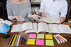 High school or college student group sitting at desk in library studying and reading, doing homework and lesson practice preparing