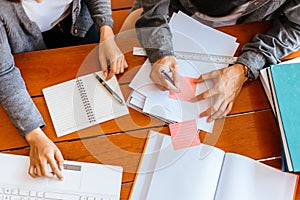 High school or college students  group catching up workbook and learning tutoring on desk and reading, doing homework, lesson