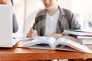 High school or college students  group catching up workbook and learning tutoring on desk and reading, doing homework, lesson