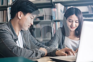 High school or college students studying and reading together in library. Student use laptop at library