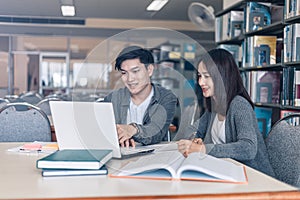 High school or college students studying and reading together in library. Student use laptop at library