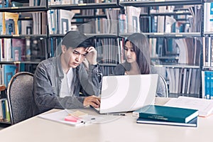 High school or college students studying and reading together in library. Student use laptop at library