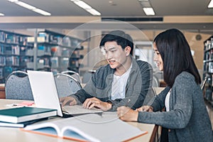 High school or college students studying and reading together in library. Student use laptop at library