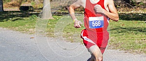 High school cross country runner finishing a 5K on a gravel straightaway with plenty of copy spzce behind him
