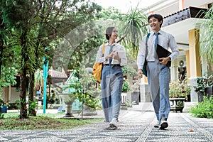 High school girl and boy walk with book and laptop