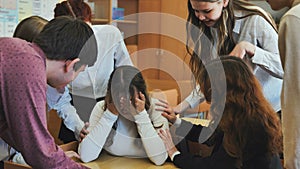 A high school girl cries and her friends comfort her.