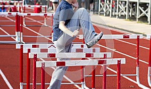 High school girl doing a hurdle warm up drill sidways over track hurdles