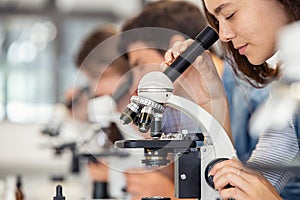 High school girl looking through microscope at school