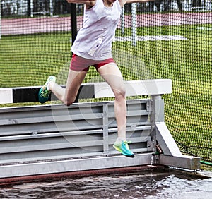 High school girls going over steeplechase barrier into water