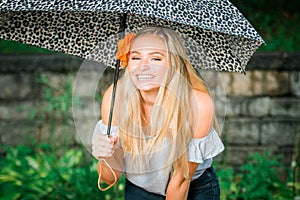 High school senior poses with umbrella for portraits on a rainy