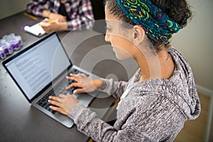 High school student girl learning online and doing homework using a laptop computer