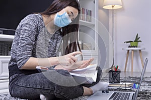 High school student girl with mask on her face using sanitizer before doing her homework