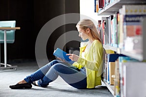 High school student girl reading book at library