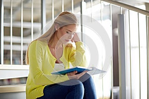 High school student girl reading book on stairs