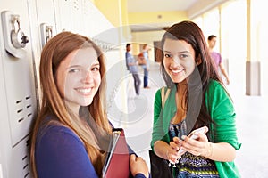 High School Students By Lockers Looking At Mobile Phone