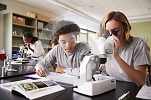 High School Students Looking Through Microscope In Biology Class photo