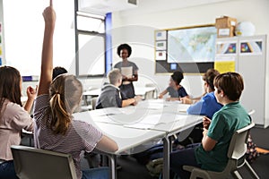 High School Students Raising Hands To Answer Question Set By Teacher In Classroom