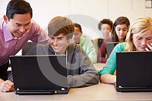 High School Students With Teacher In Class Using Laptops